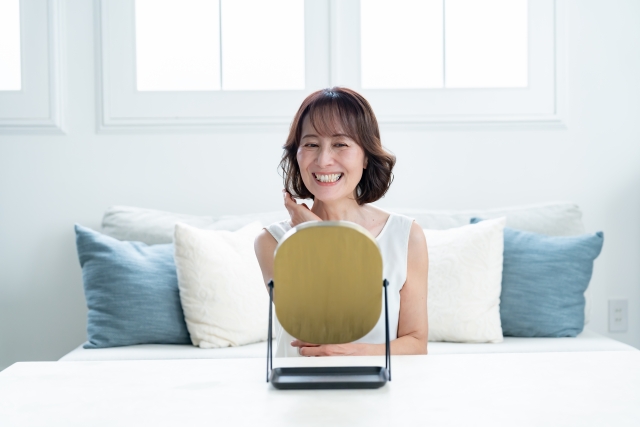 鏡を見てほほ笑む女性