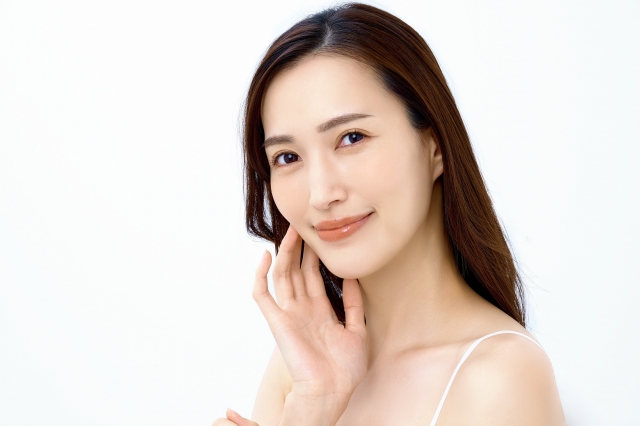 肌に触れてほほ笑む女性